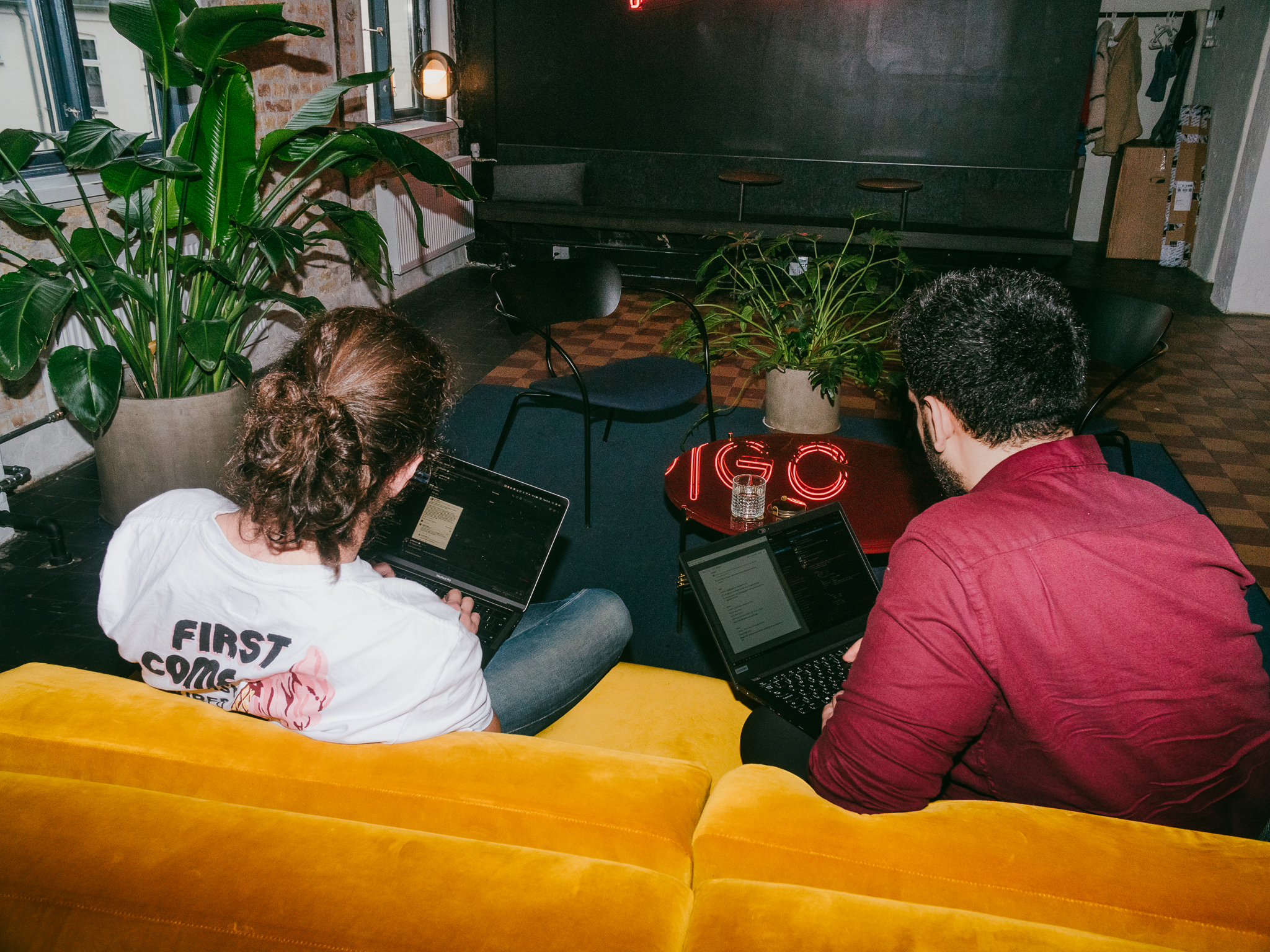 Two Pleo employees on a sofa working on laptops